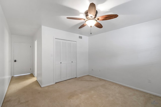 unfurnished bedroom featuring ceiling fan, light colored carpet, and a closet