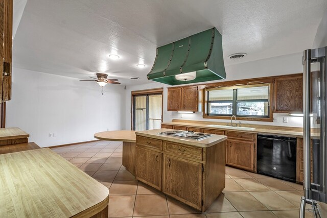 kitchen with a textured ceiling, stainless steel appliances, sink, light tile patterned floors, and a kitchen island