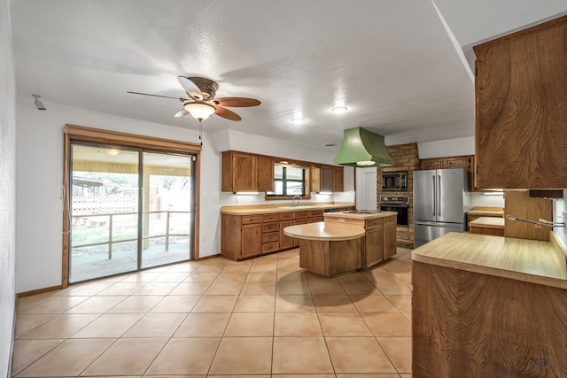 kitchen with a textured ceiling, ceiling fan, black appliances, light tile patterned floors, and a center island