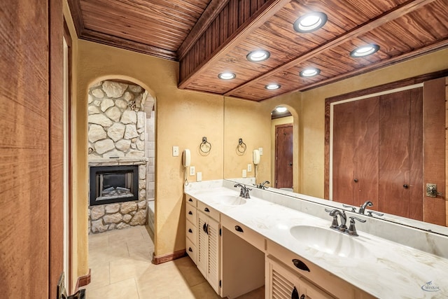 bathroom featuring vanity, a bath, tile patterned floors, a stone fireplace, and wood ceiling