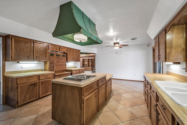 kitchen featuring a center island, light tile patterned floors, sink, and stainless steel gas cooktop