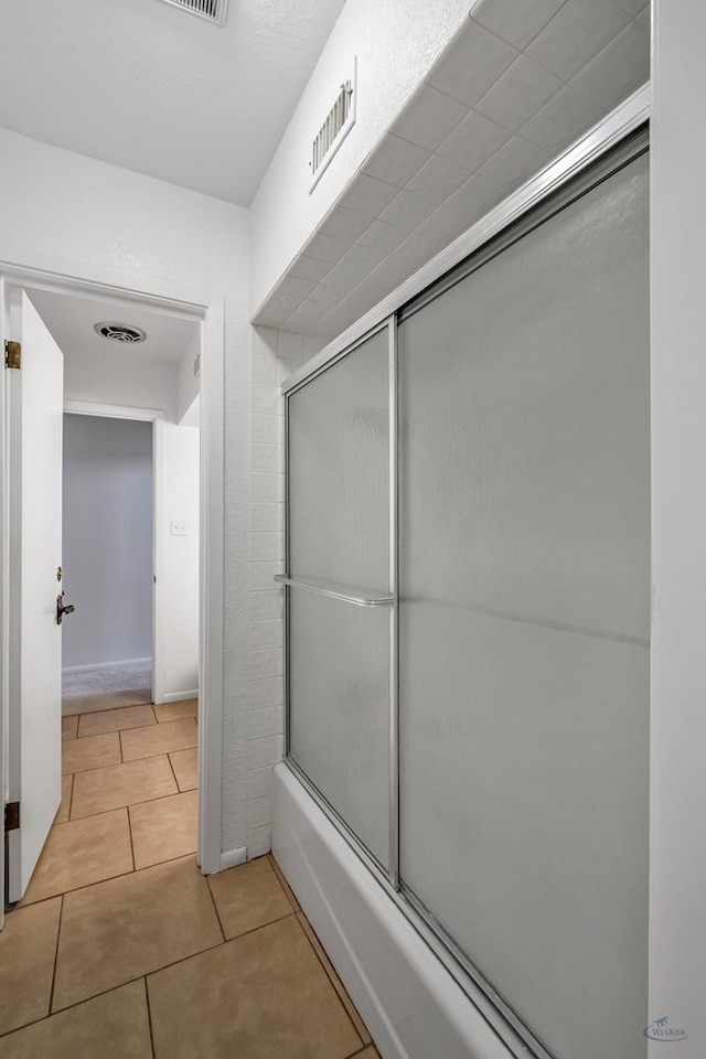 bathroom featuring tile patterned flooring and bath / shower combo with glass door