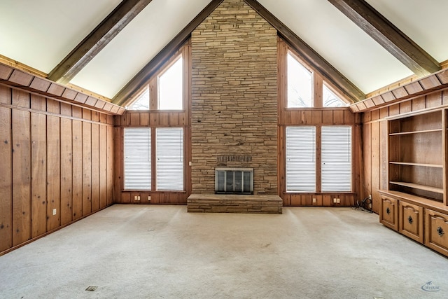 unfurnished living room with wooden walls, high vaulted ceiling, and a healthy amount of sunlight