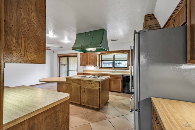 kitchen featuring light tile patterned flooring, a textured ceiling, stainless steel appliances, sink, and range hood