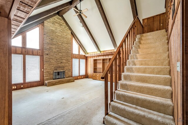 unfurnished living room featuring beamed ceiling, carpet floors, high vaulted ceiling, and a fireplace