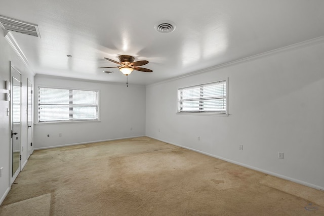 carpeted empty room featuring a wealth of natural light, crown molding, and ceiling fan