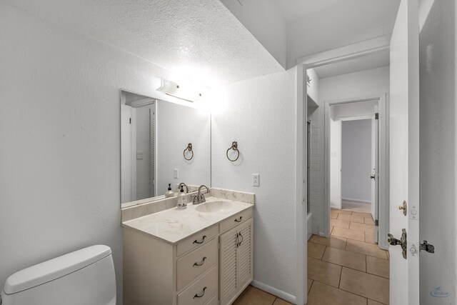 bathroom featuring tile patterned flooring, vanity, a textured ceiling, and toilet