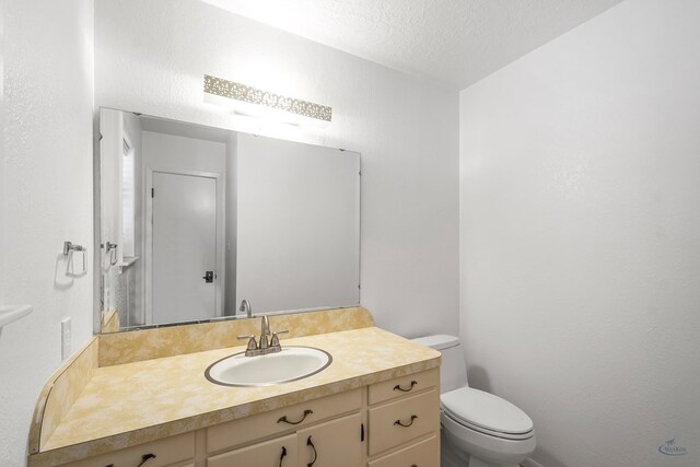 bathroom featuring vanity, a textured ceiling, and toilet