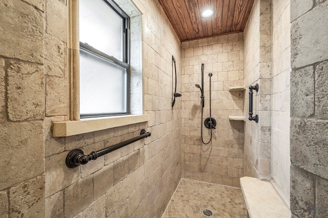 bathroom featuring a tile shower and wood ceiling