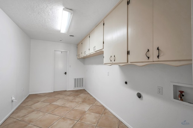 laundry room with cabinets, hookup for a washing machine, hookup for an electric dryer, a textured ceiling, and light tile patterned floors