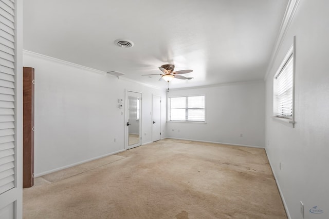 spare room featuring ceiling fan, crown molding, and light carpet