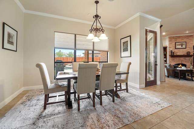 dining space featuring a notable chandelier, light tile patterned flooring, crown molding, and a brick fireplace