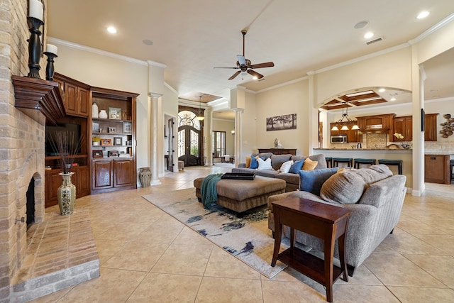 tiled living room with ornate columns, ceiling fan, and ornamental molding