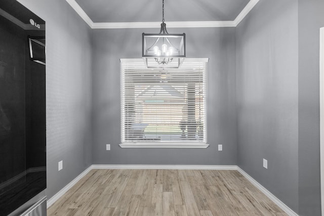 empty room with light wood-type flooring, ornamental molding, and a notable chandelier