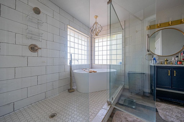 bathroom with vanity, tile walls, plus walk in shower, and an inviting chandelier