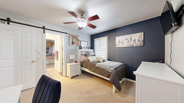 carpeted bedroom featuring ceiling fan, a barn door, a textured ceiling, and ensuite bath