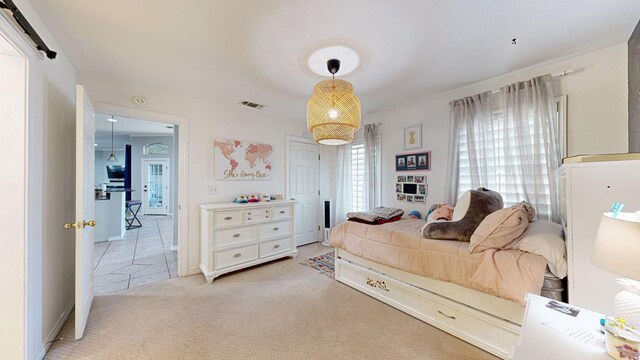 bedroom with a barn door and light colored carpet