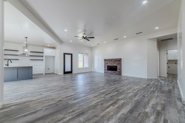 1708 E Main St, Brownfield, TX 79316 - unfurnished living room featuring ceiling fan, light wood finished floors, a brick fireplace, baseboards, and recessed lighting