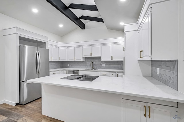 905 Mountain Park Dr, Big Spring, TX 79720 - kitchen with appliances with stainless steel finishes, a sink, a peninsula, white cabinets, and decorative backsplash