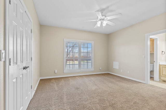 unfurnished bedroom featuring ensuite bath, light colored carpet, a closet, and ceiling fan