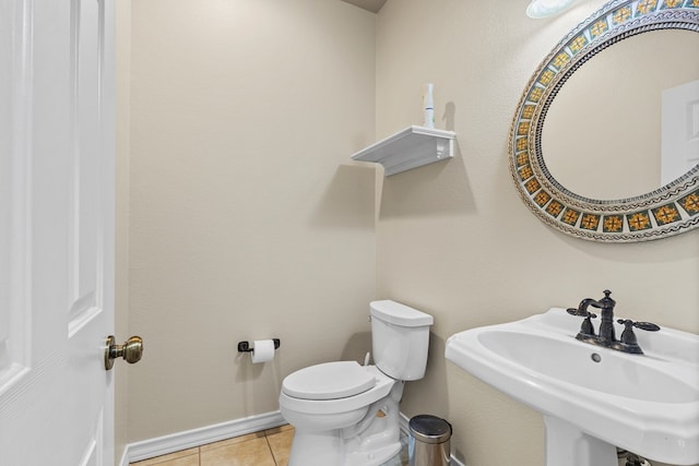 bathroom featuring toilet, sink, and tile patterned flooring