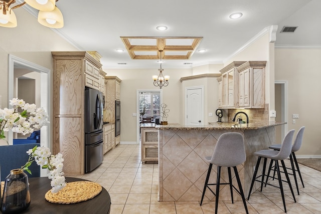 kitchen featuring black fridge with ice dispenser, a breakfast bar area, kitchen peninsula, and decorative backsplash