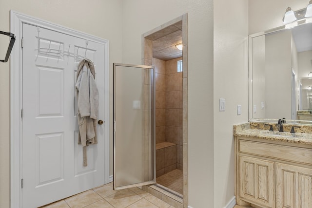 bathroom with a shower with door, vanity, and tile patterned floors