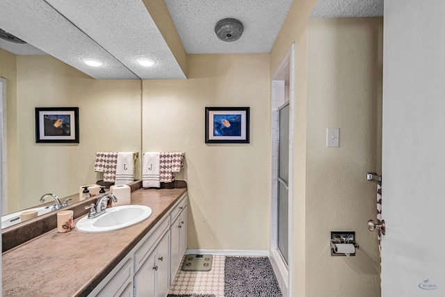 bathroom featuring a textured ceiling, a shower stall, vanity, and baseboards