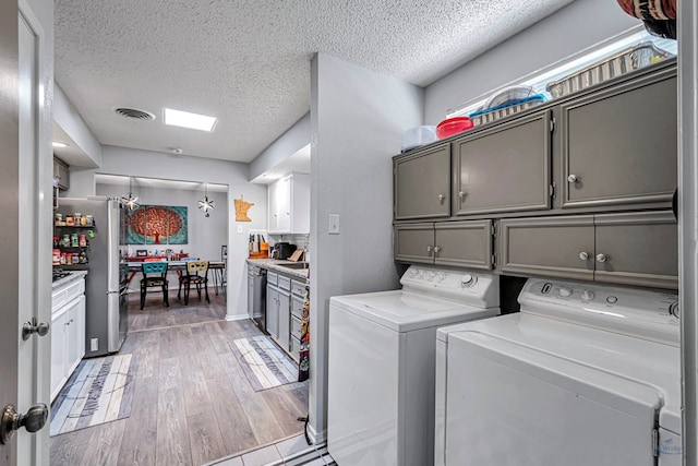 washroom featuring cabinet space, visible vents, wood finished floors, independent washer and dryer, and a textured ceiling