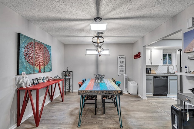 dining room featuring light wood-style floors, a textured ceiling, and baseboards