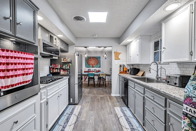 kitchen with visible vents, dark wood-style flooring, gray cabinets, stainless steel appliances, and a sink