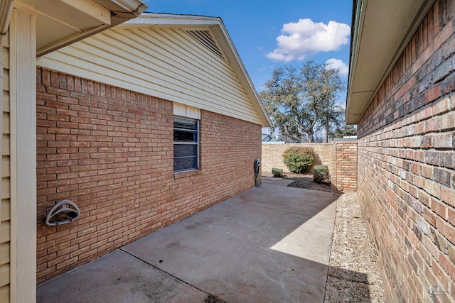 view of property exterior featuring a patio, brick siding, and a fenced backyard