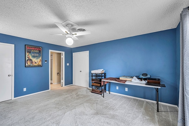 interior space with carpet, ceiling fan, a textured ceiling, and baseboards