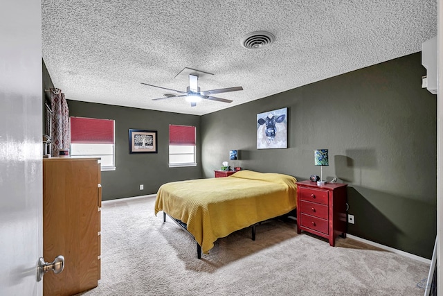 bedroom featuring a textured ceiling, carpet floors, a ceiling fan, visible vents, and baseboards