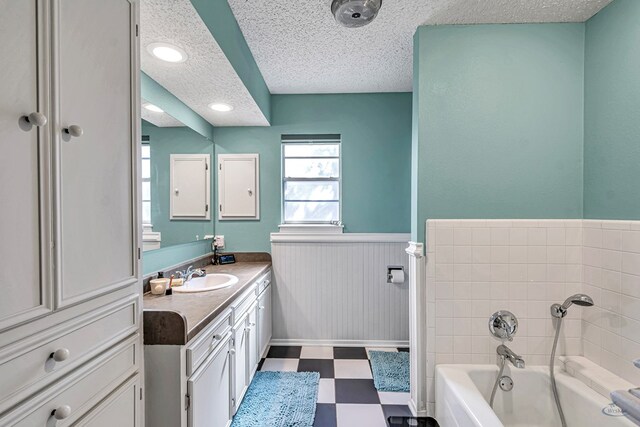 full bath with wainscoting, a garden tub, a textured ceiling, and tile patterned floors