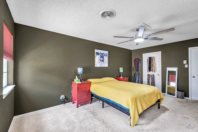 bedroom featuring ceiling fan, a textured ceiling, visible vents, and carpet flooring