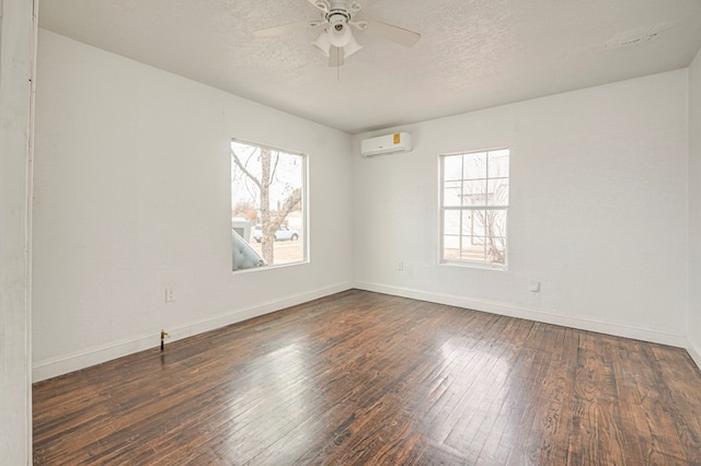 empty room with a wall mounted air conditioner, a textured ceiling, ceiling fan, and dark wood-type flooring