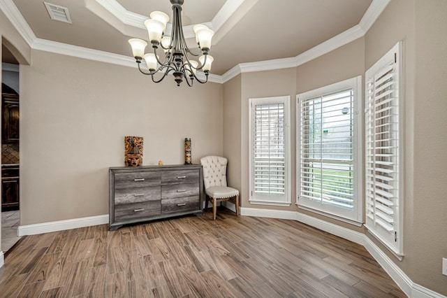 unfurnished room featuring wood finished floors, baseboards, ornamental molding, and an inviting chandelier