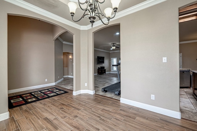unfurnished dining area featuring wood finished floors, arched walkways, a chandelier, and crown molding