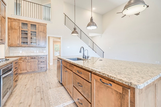 1221 Porterfield Rd, Midland, TX 79705 - kitchen with a sink, appliances with stainless steel finishes, light wood-style floors, glass insert cabinets, and decorative backsplash