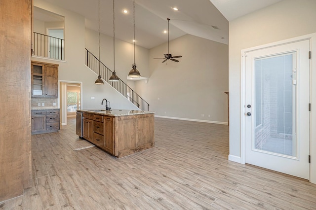 1221 Porterfield Rd, Midland, TX 79705 - kitchen featuring brown cabinets, light wood-style flooring, pendant lighting, an island with sink, and baseboards