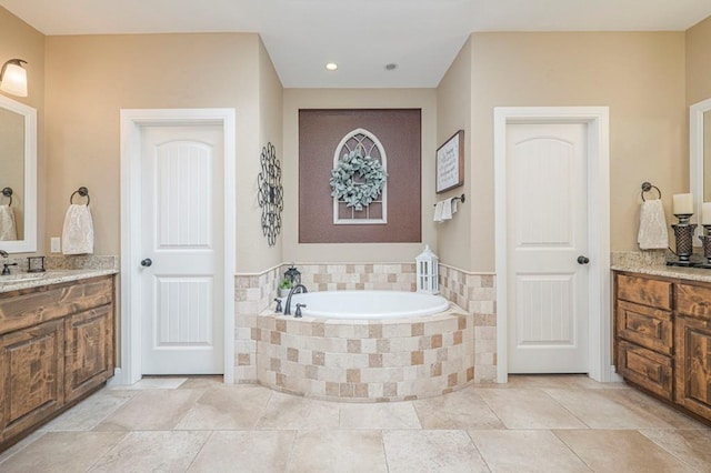 bathroom with tiled tub and vanity