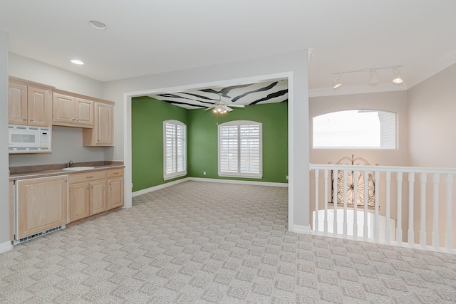 kitchen with sink, light brown cabinetry, light carpet, and white microwave