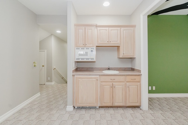 kitchen with sink, white microwave, and light brown cabinets