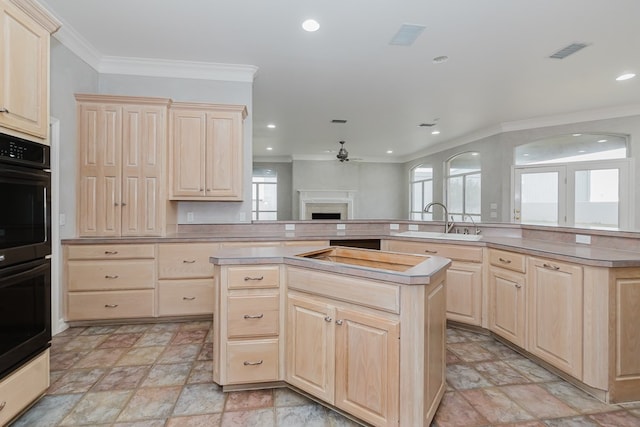 kitchen with light brown cabinetry, a kitchen island, crown molding, and sink