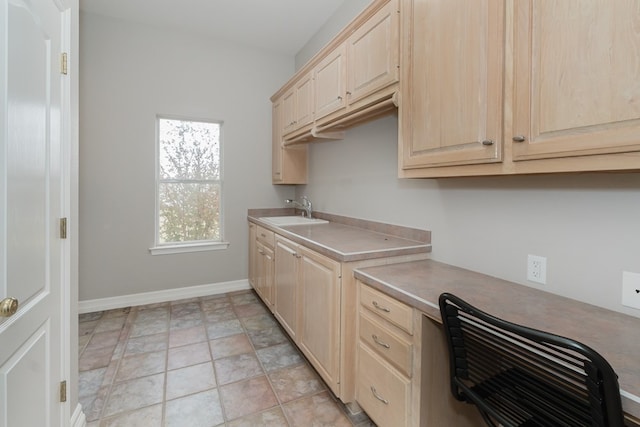 kitchen featuring light brown cabinets, built in desk, and sink