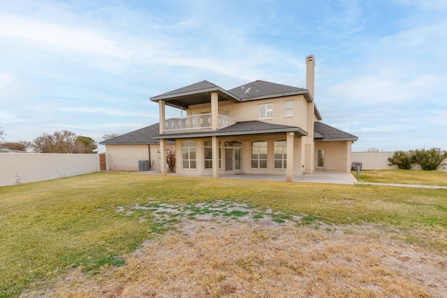 back of property with central AC unit, a patio area, a balcony, and a yard