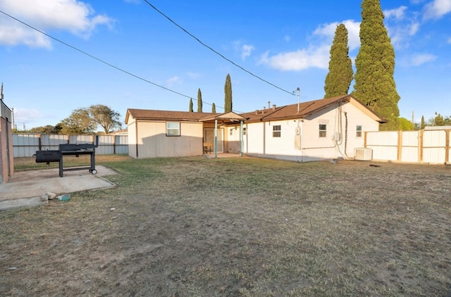 rear view of property featuring a patio, a yard, and central AC