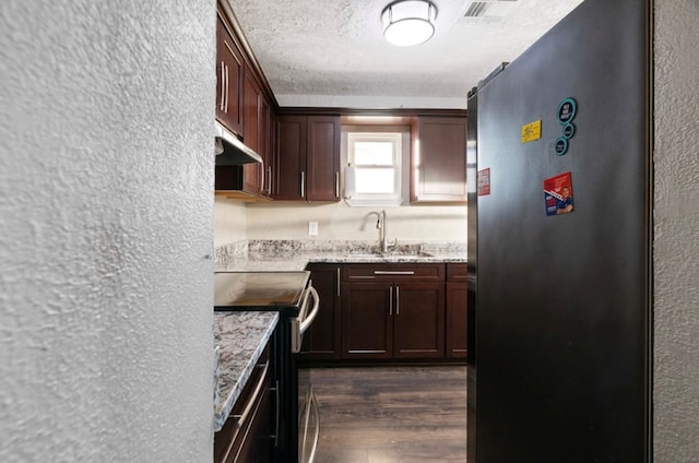 kitchen featuring light stone counters, a textured ceiling, stainless steel appliances, sink, and dark hardwood / wood-style floors