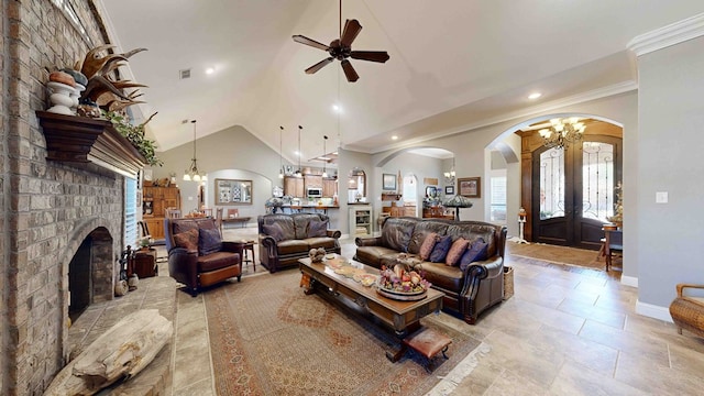 living room featuring ceiling fan with notable chandelier, crown molding, high vaulted ceiling, and a brick fireplace